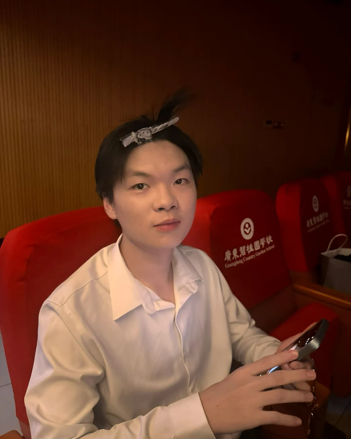 Jacky Huang in a white shirt, sitting in a theater.