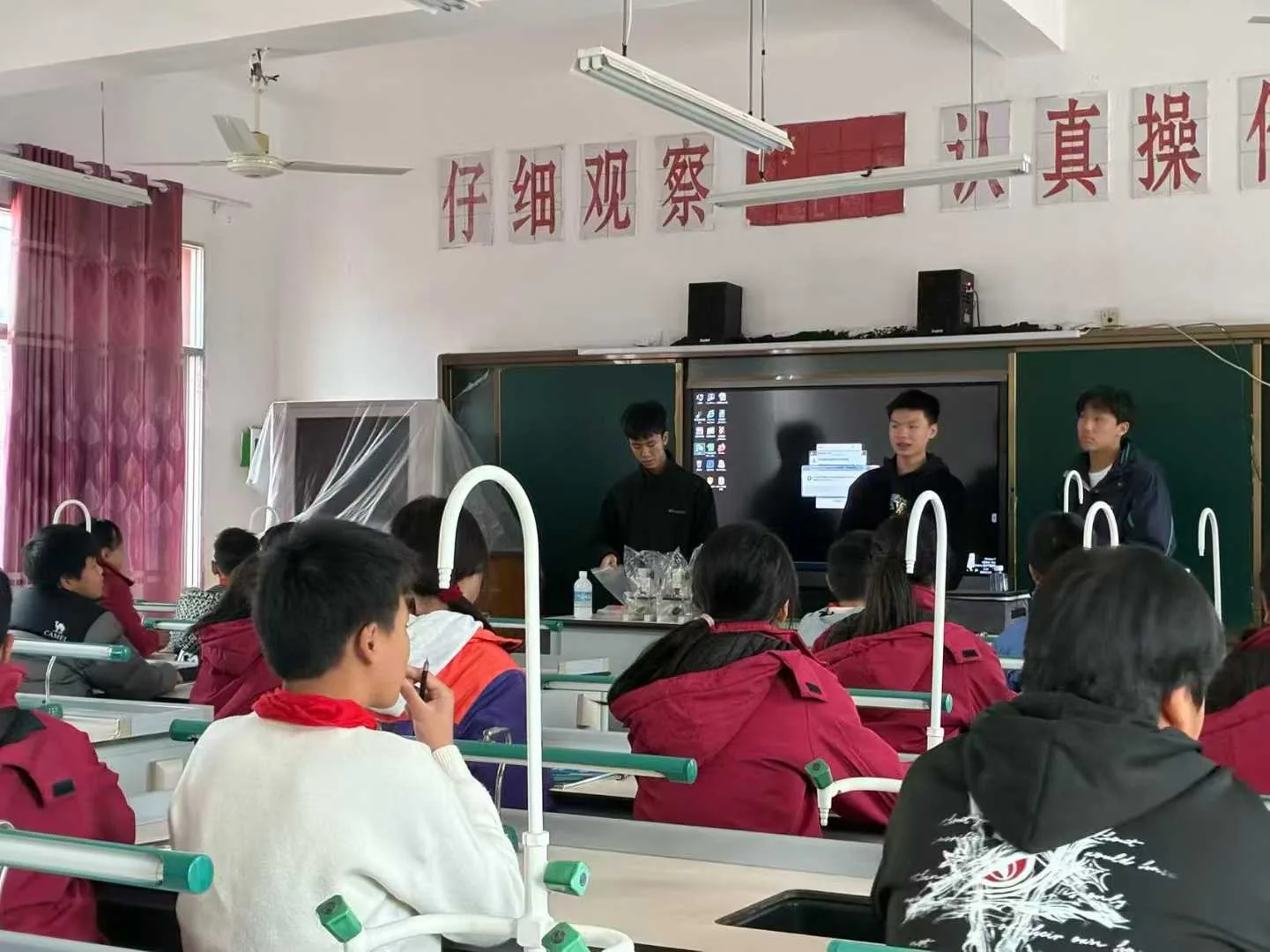 Students in a rural classroom, photographed from behind.